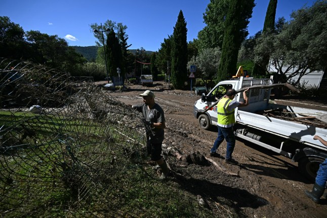 Workers clear debris from a mud-covered street in Le Lavandou