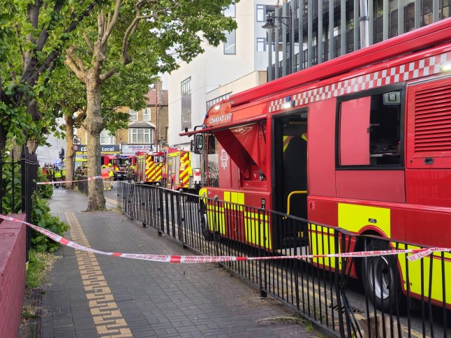 A significant fire has broken out at a shop with residential flats above on High Street North, East Ham, with ten fire engines and approximately 70 firefighters battling the blaze this evening, Thursday 29 May 2025. The fire was first reported to London Fire Brigade (LFB) at 19:02, when Control Officers received the first of 12 emergency calls reporting smoke and flames emerging from a mid-terraced commercial property. Blaze Declared Major Incident Firefighters arriving from East Ham, Plaistow, Stratford, and surrounding fire stations found half of the ground floor shop unit alight, with fears the fire could spread to the dwellings located on the floors above. A major incident has been declared by the Met Police as crews work swiftly to contain the flames and prevent further escalation. What We Know So Far: Location: High Street North, East Ham, E6 Time of first call: 19:02 BST Response: 10 fire engines, approx. 70 firefighters Involved structure: Shop with residential flats above Fire status: Half of shop alight, crews actively tackling blaze Injuries: No confirmed casualties at this time Public Advice Authorities are urging people to avoid the area and keep windows and doors shut due to thick smoke affecting surrounding streets. High Street North remains partially closed, with diversions in place. The incident is likely to cause significant travel disruption this evening. London Fire Brigade Statement An LFB spokesperson said: ???Crews are working in challenging conditions to bring the fire under control. Our firefighters are using breathing apparatus, hose reels and main jets to tackle the flames and protect adjacent properties.???