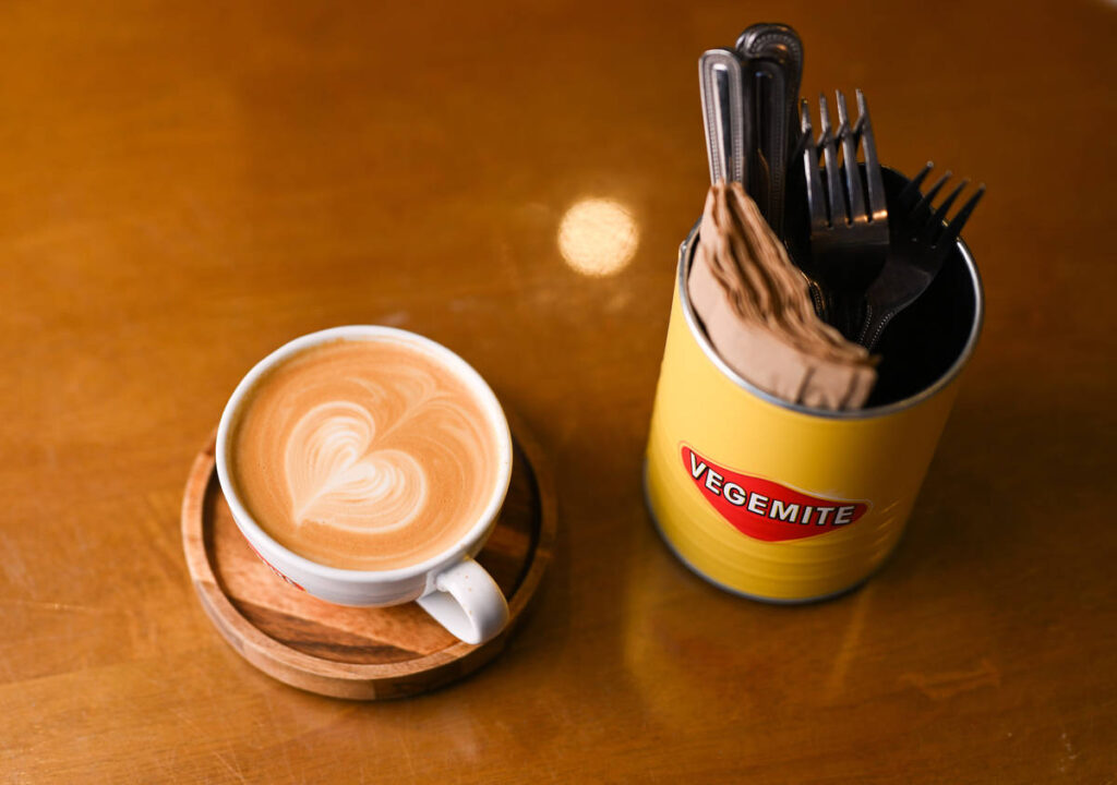 a cup of coffee next to some cutlery in a vegemite themed tin