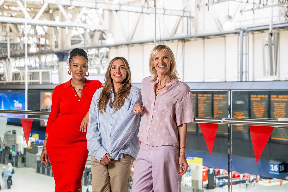 Yinka Bokinni, Melanie Blatt and Jo Whiley stood on station concourse with train announcement screens in background