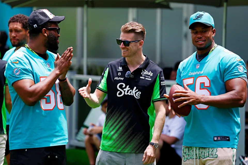 May 1, 2025; Miami Gardens, FL, USA; Sauber driver Nico Hulkenberg (center) greets Miami Dolphins players Will Bradley-King (left) and Quinton Bell (right) ahead of the F1 Miami Grand Prix at Miami International Autodrome. Mandatory Credit: Peter Casey-Imagn Images