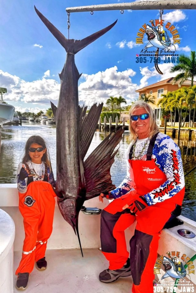Captain Mark "The Shark" Quartiano with a young girl and a large sailfish.
