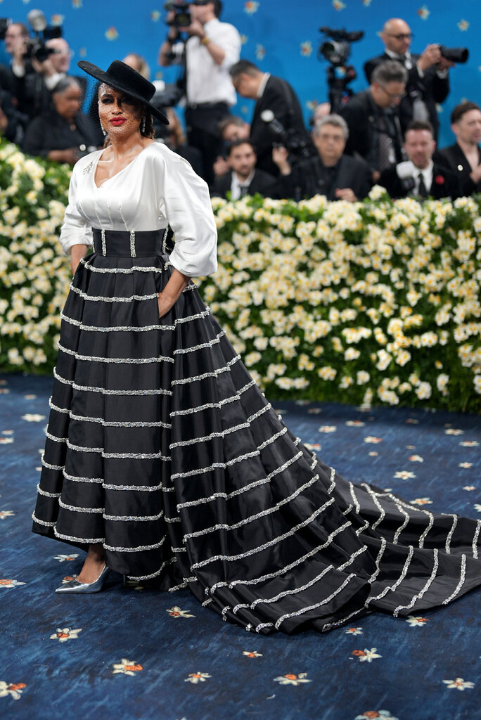 Ava DuVernay is wearing a striped skirt, white bodice and black hat with a veil.