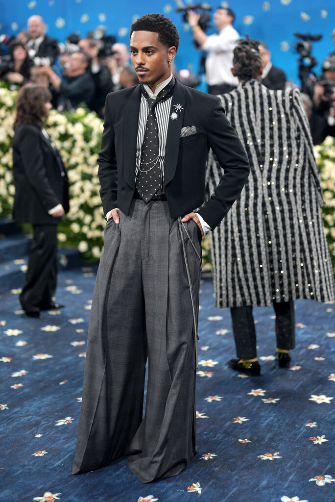 Keith Powers is wearing a suit with a polka dot tie and chain details.