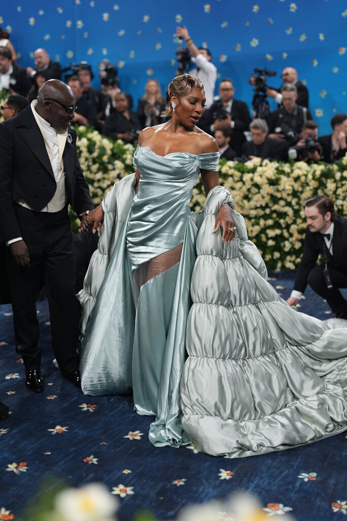 Serena Williams is wearing a teal dress and matching shawl.