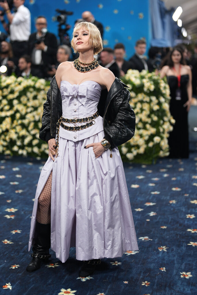Angèle is wearing a light purple dress and a black leather jacket.