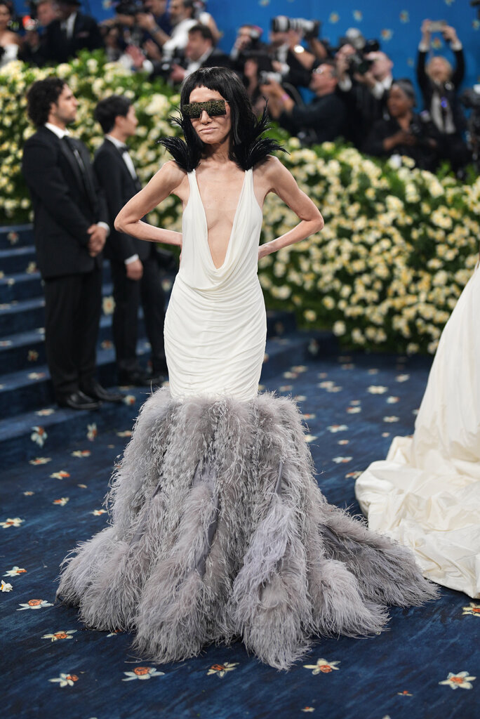 Vera Wang is wearing a white scoop-neck dress with a gray feathered skirt.