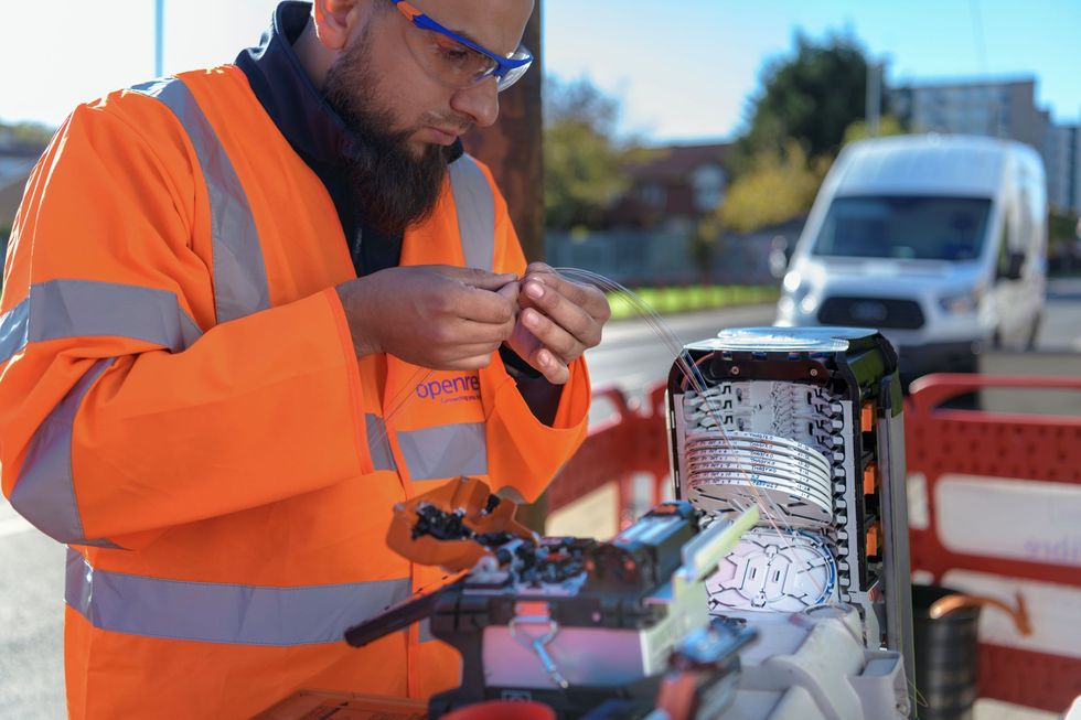 an openreach engineer is pictured holding a fibre optic cable at one of thousands of exchanges across the UK