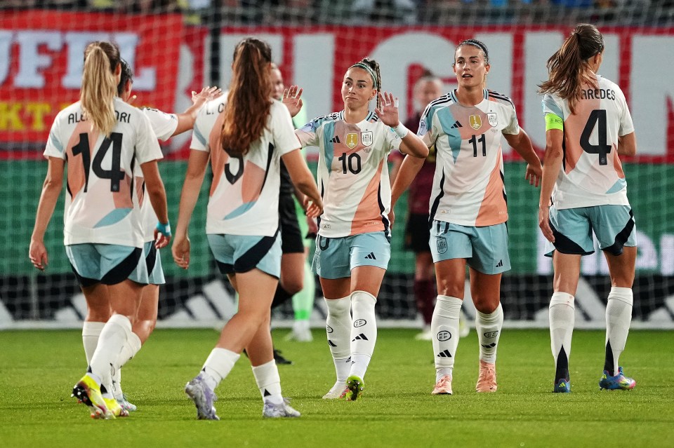 Spanish and Belgian women's soccer players conversing after a match.