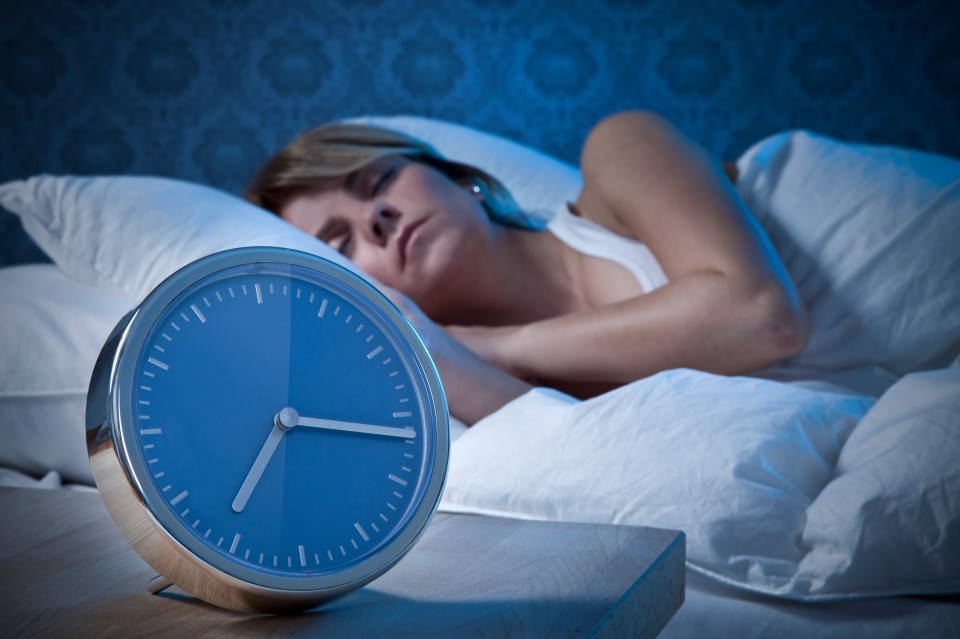Woman sleeping soundly next to an alarm clock.