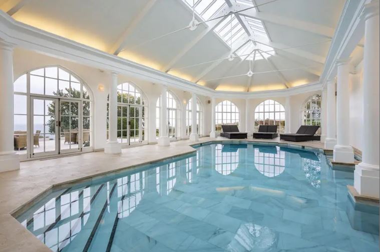 Indoor pool in a large, bright room with many windows.