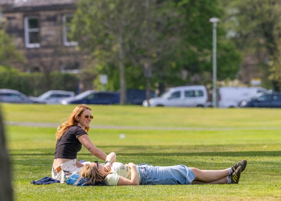 Two women relaxing on a grassy area.