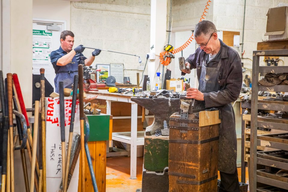 Two men crafting golf clubs in a workshop.