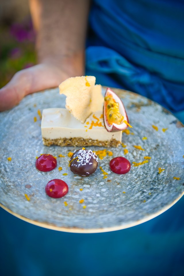Dessert plate with a raw vegan dessert, passionfruit, and chocolate truffle.