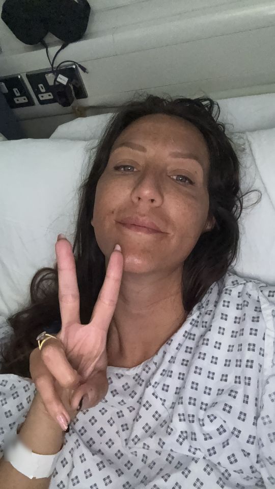 Woman in hospital gown giving peace sign.