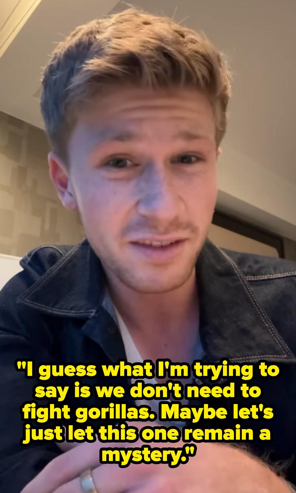 Person in a casual setting wearing a black denim jacket over a white shirt, looking at the camera