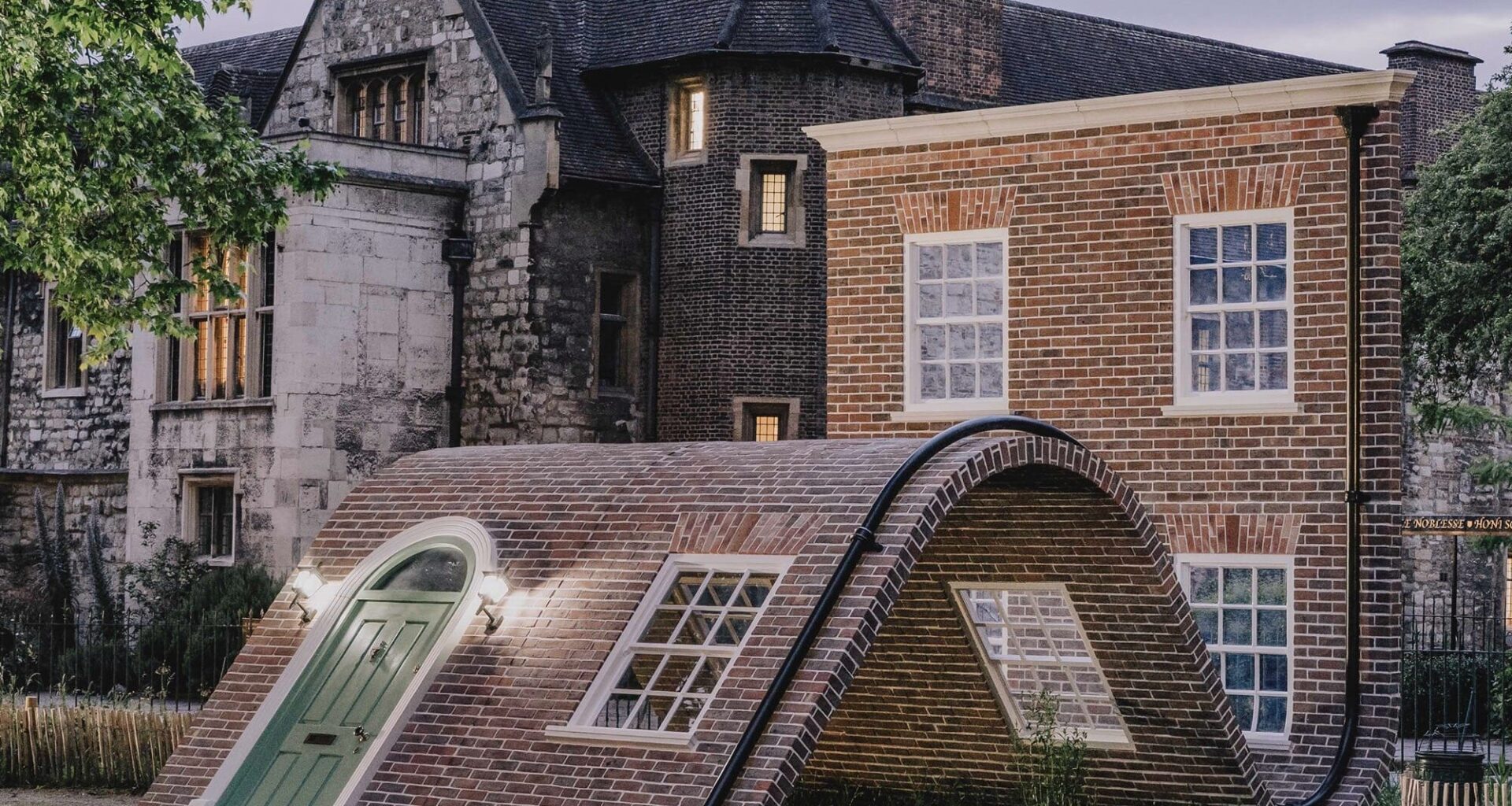 a public art piece in a a park featuring the facade of a London townhouse that appears to sit on the ground with its knees up