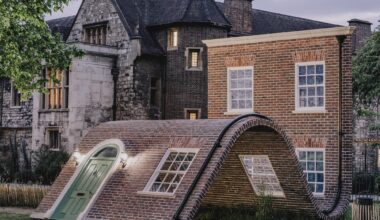 a public art piece in a a park featuring the facade of a London townhouse that appears to sit on the ground with its knees up