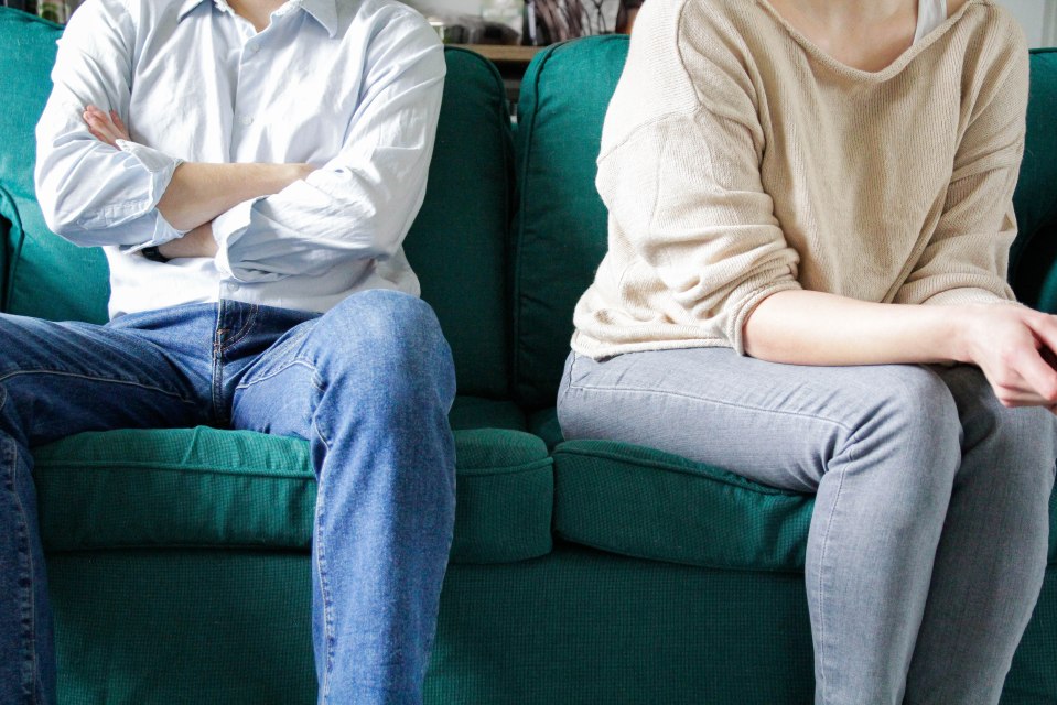 Couple sitting apart on a green sofa.
