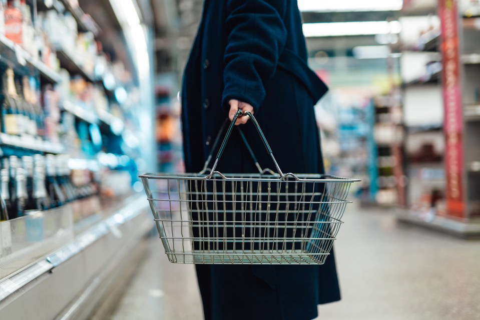 Woman carrying an empty shopping basket in a supermarket.