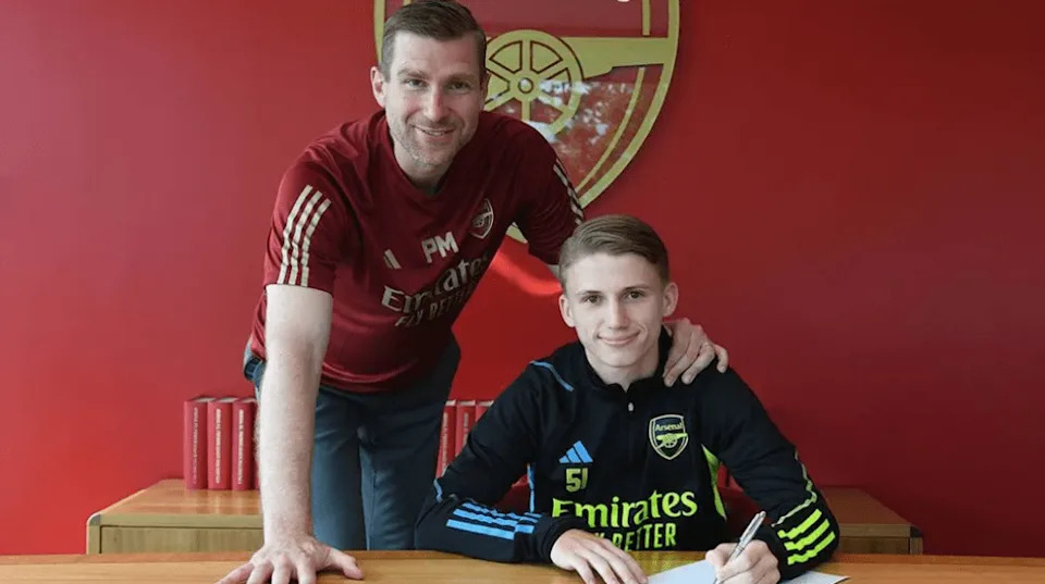 Jimi Gower signing his first professional contract with Arsenal, alongside Per Mertesacker (Photo via Arsenal.com)