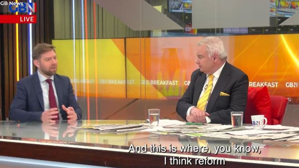 Two men in suits sitting at a table discussing reform on a news program.