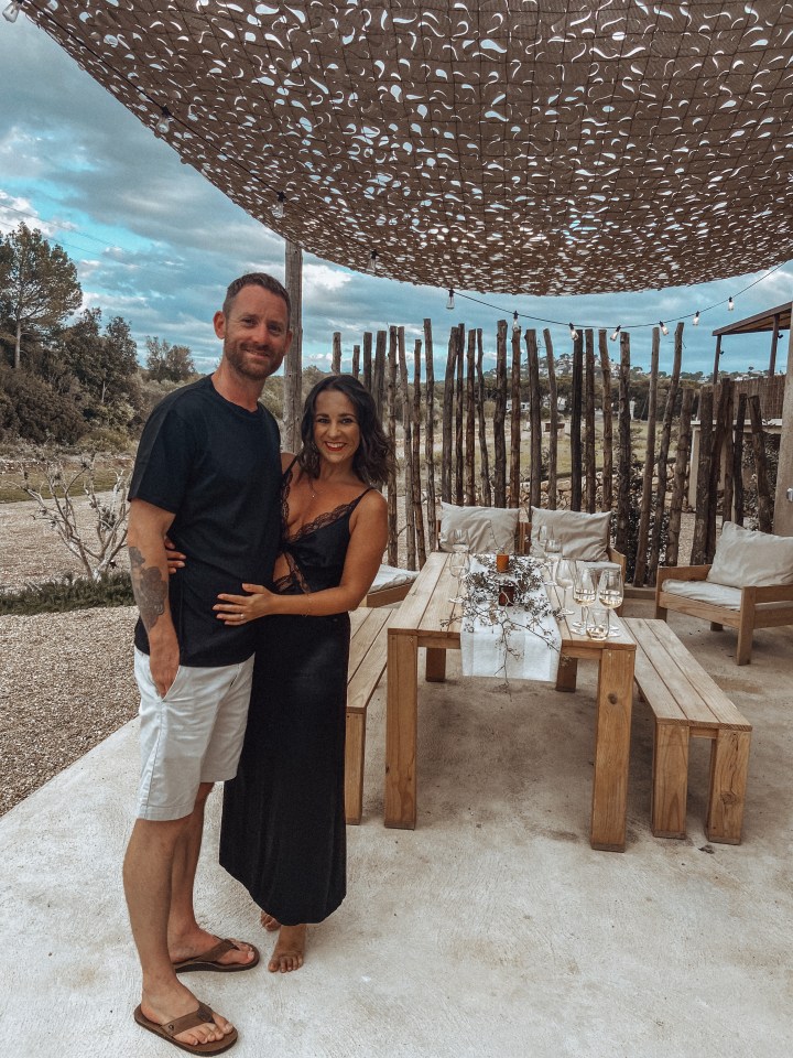 Couple standing together outdoors near a table set for a meal.