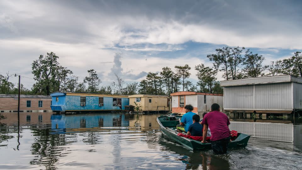 A family travel by boat to their home after it flooded during Hurricane Ida on August 31, 2021 in Barataria, Louisiana. - Brandon Bell/Getty Images