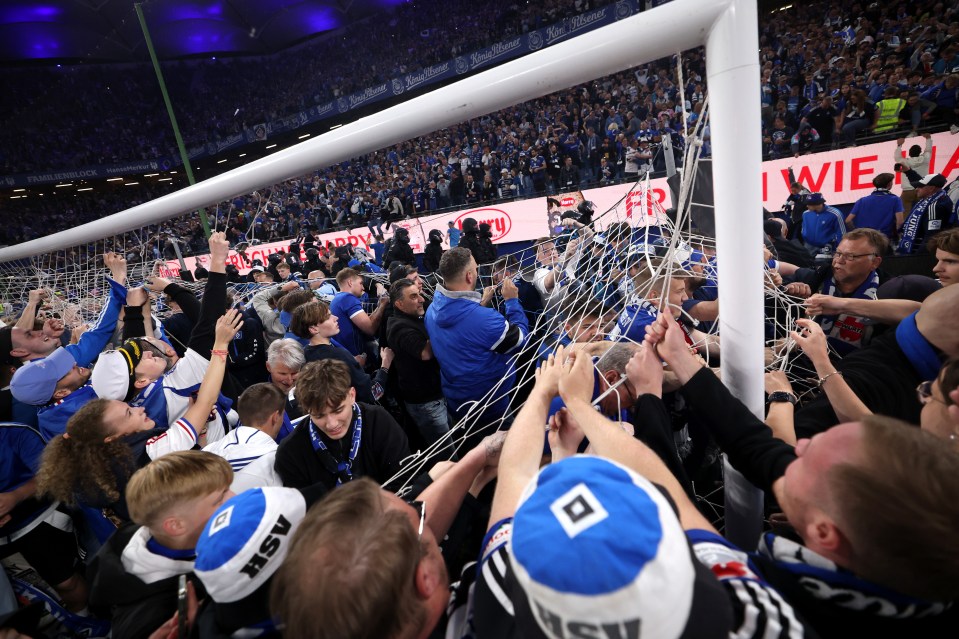 Fans celebrating a soccer team's promotion by ripping down the goal net.