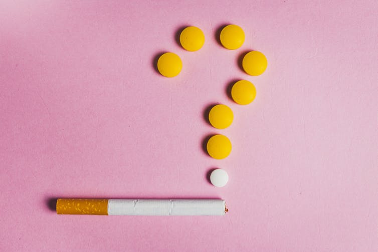 Cigarette with round pills arranged above it in the shape of a question mark