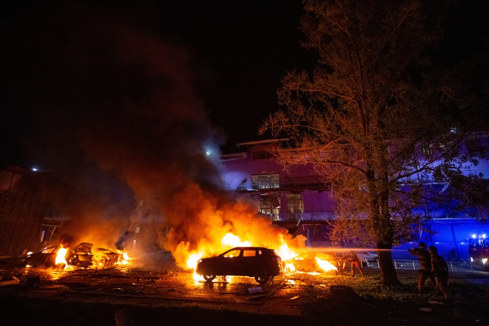Firefighters extinguishing burning cars at the site of a drone strike in Kyiv.