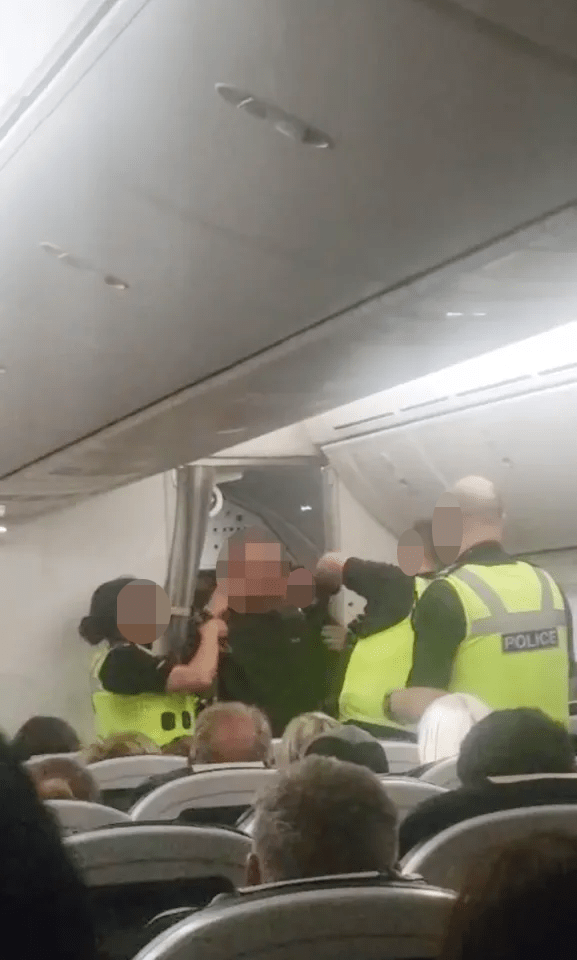 A passenger being restrained by airline crew on a plane.