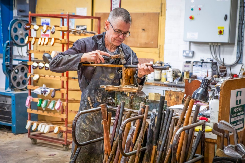 A craftsman hand-making golf clubs in a workshop.