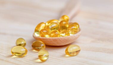Vitamin D supplements on a wooden spoon, some have spilled onto the table.