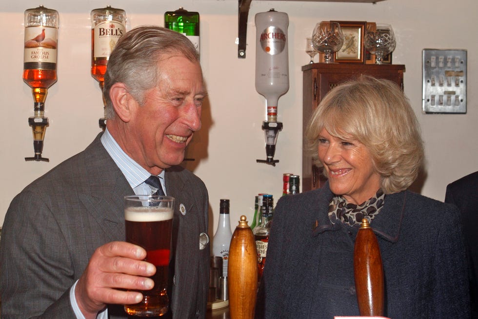 prince charles, prince of wales pulls a pint of newtons drop beer as camilla, duchess of cornwall looks on