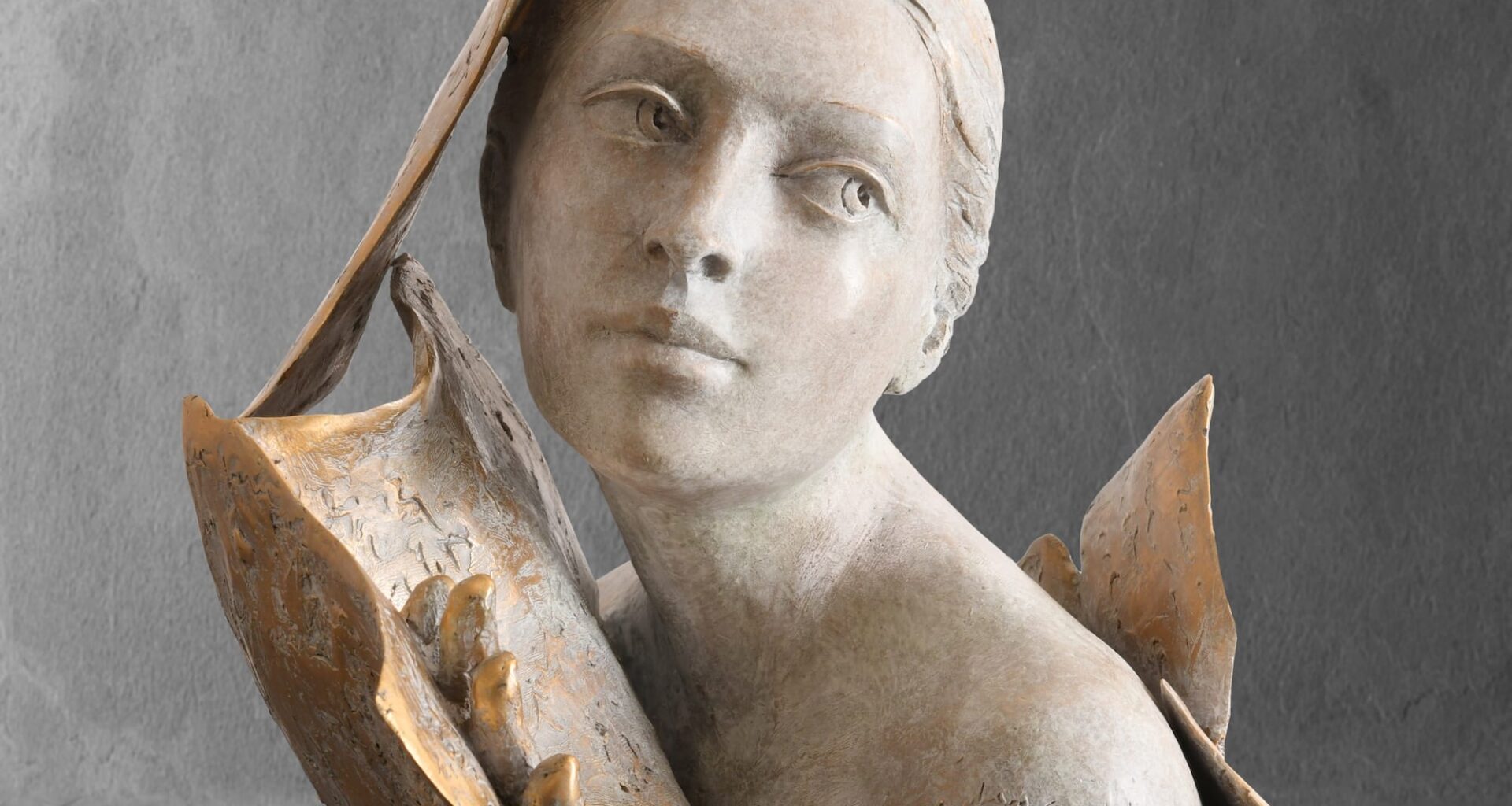 a sculpture of a woman's head and shoulders, surrounded by book or manuscript pages