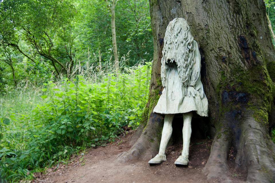Statue of a girl hiding behind a tree.