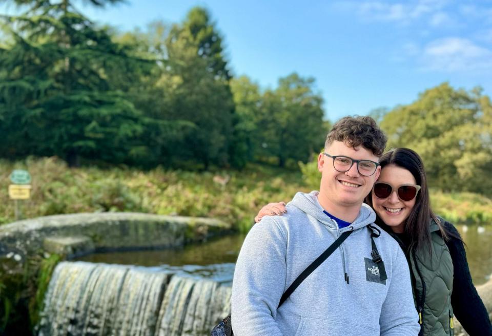 A young man and woman smiling for a photo in a park.