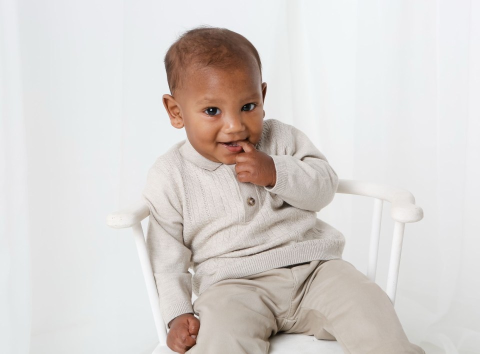 Baby boy sitting in a white chair.