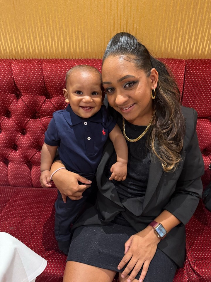 Woman holding her baby on a red couch.