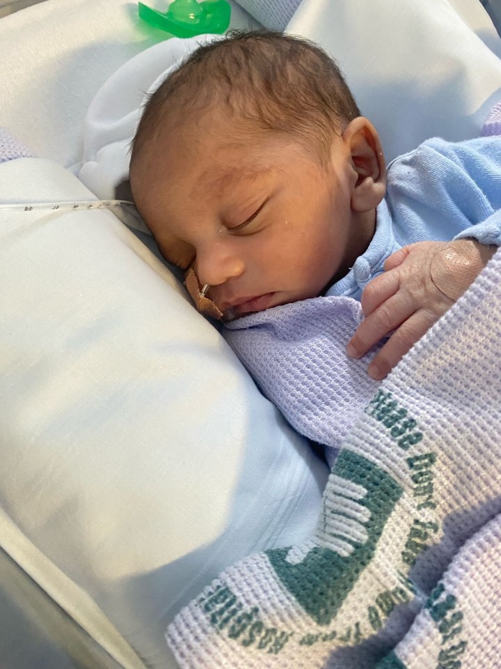 Newborn baby sleeping in a hospital crib.