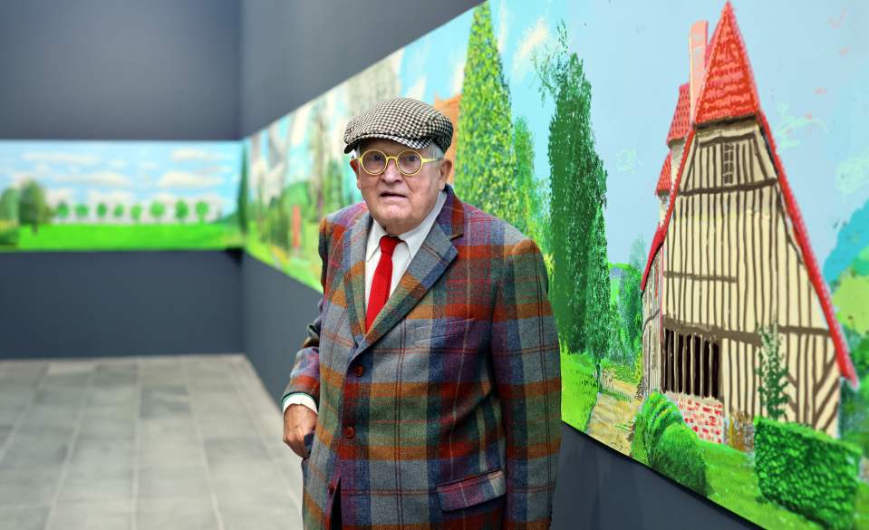 David Hockney standing in front of his painting, "A Year in Normandy."