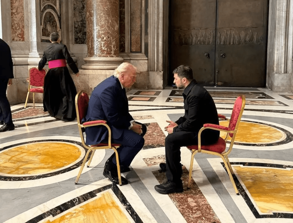 Donald Trump and another man sitting in chairs, in conversation.