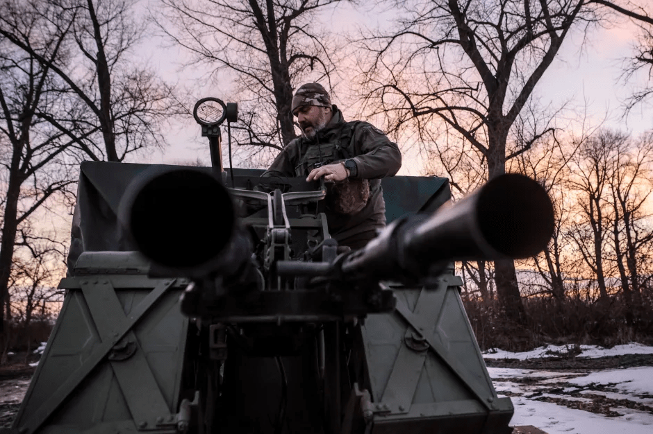 Man operating a military vehicle's anti-aircraft gun.