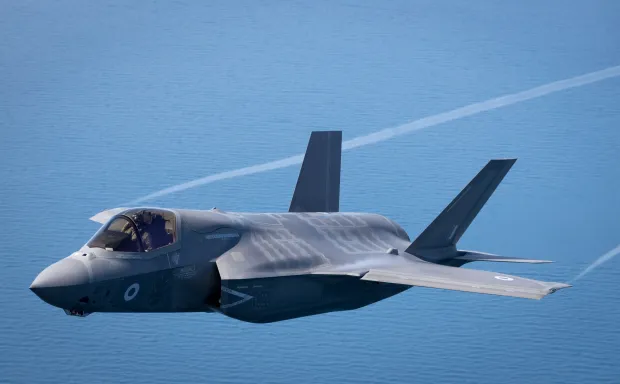 F-35B Lightning II fighter jet in flight over water.