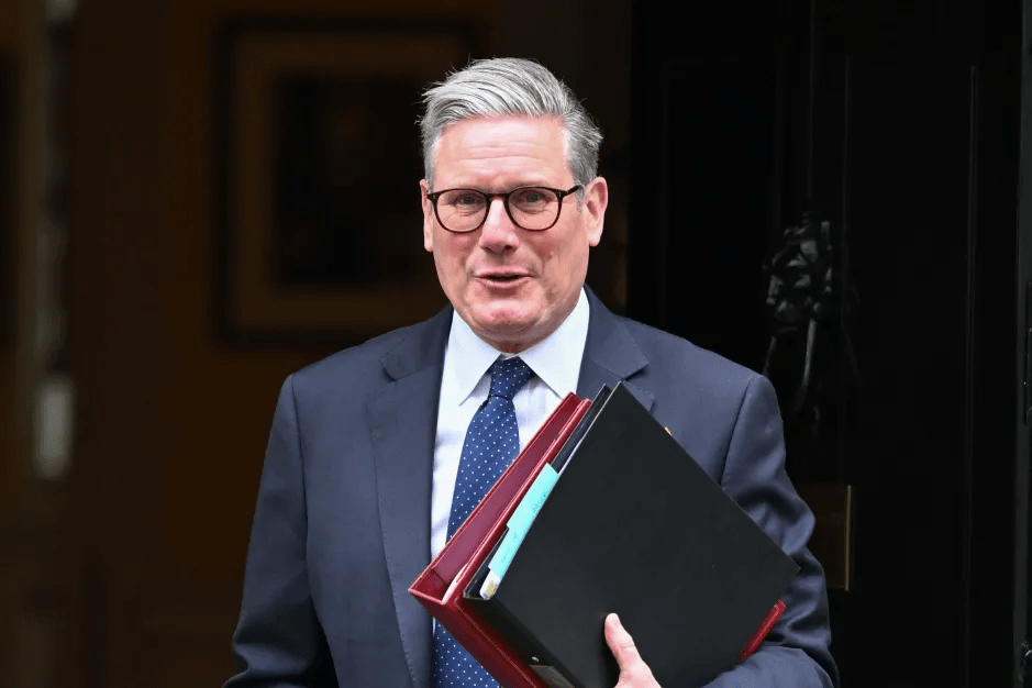 A man in a suit and glasses carrying files.