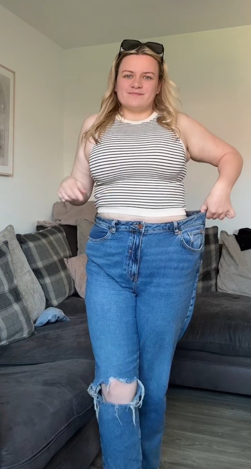 Woman showing off weight loss by holding up loose jeans.