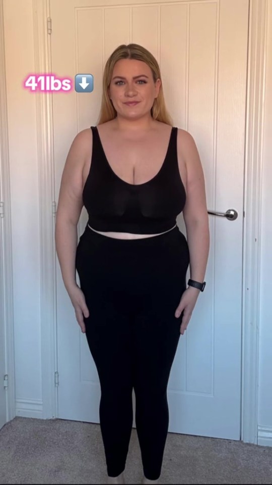 Woman in black top and leggings showing 41 lbs weight loss.