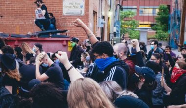 Masked people with their fists raised in a form of protest