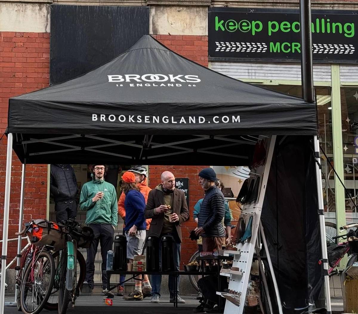 people stood under with gazebo outside keep pedalling